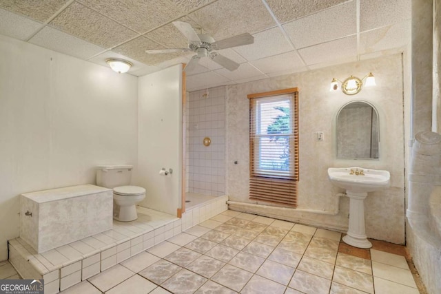 full bath featuring tile patterned floors, toilet, a drop ceiling, and a tile shower