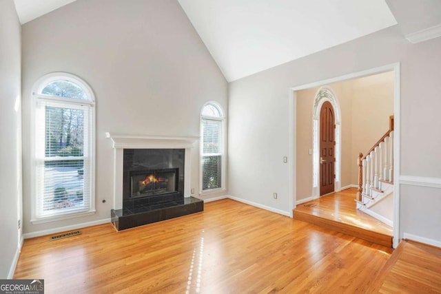 unfurnished living room featuring visible vents, wood finished floors, stairway, a fireplace, and baseboards