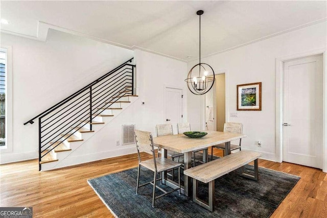 dining space with visible vents, baseboards, stairs, an inviting chandelier, and wood finished floors