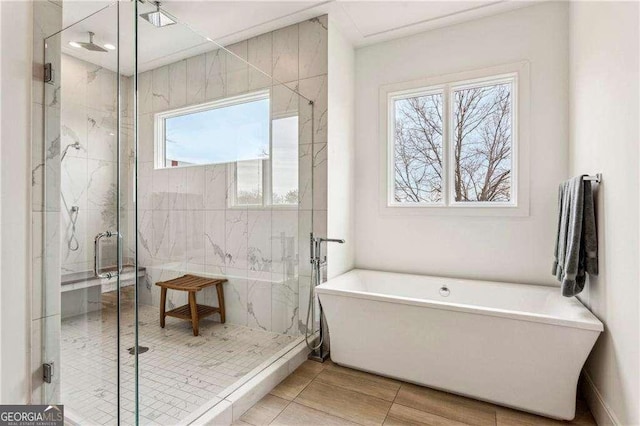 full bathroom featuring a marble finish shower and a freestanding tub