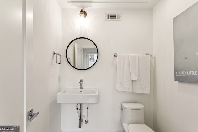 bathroom with visible vents, toilet, and a sink