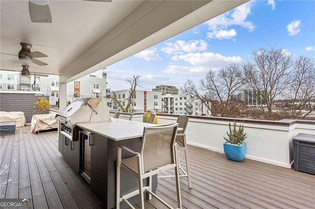 wooden terrace with outdoor wet bar, grilling area, exterior kitchen, and ceiling fan