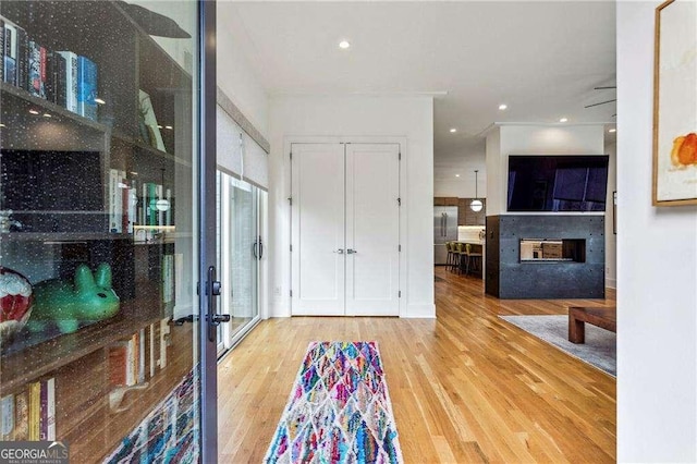 foyer with a multi sided fireplace, recessed lighting, and wood finished floors