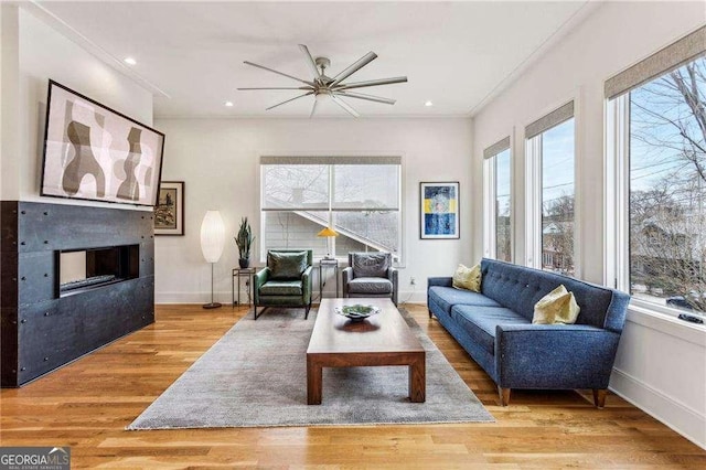 living room with plenty of natural light, a fireplace, baseboards, and wood finished floors