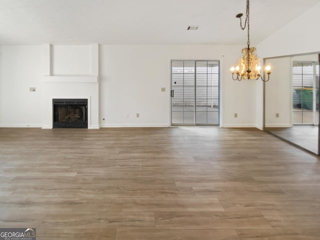 unfurnished living room with visible vents, a fireplace, light wood-type flooring, and vaulted ceiling