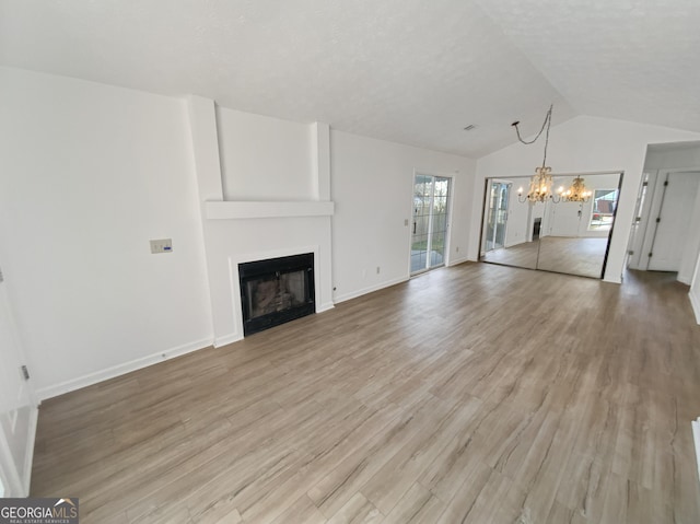 unfurnished living room featuring light wood-style flooring, a chandelier, a fireplace, and vaulted ceiling