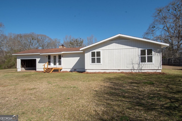 rear view of property with an attached garage, a yard, and crawl space