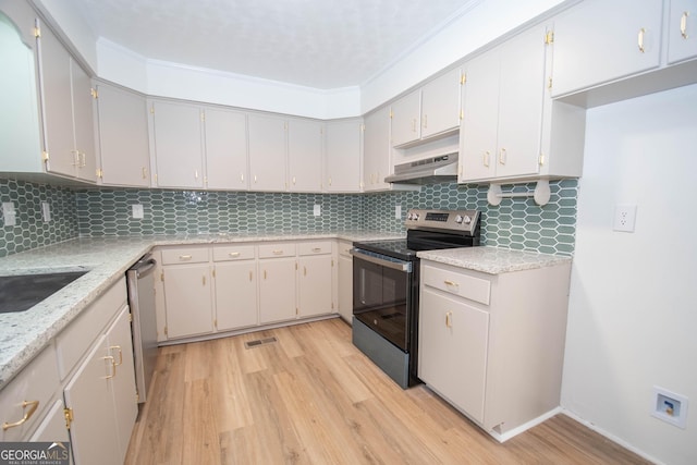 kitchen with under cabinet range hood, stainless steel appliances, light wood-style flooring, and decorative backsplash