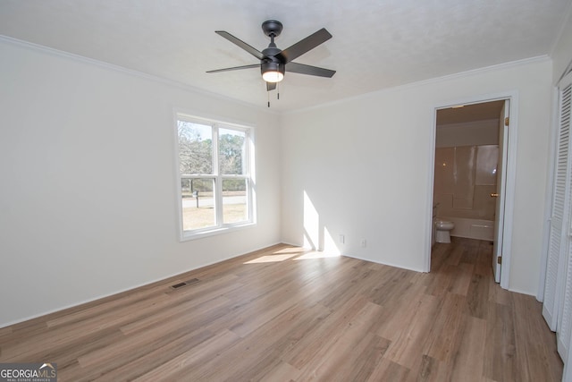 unfurnished bedroom with visible vents, ensuite bath, light wood-style flooring, ornamental molding, and a closet