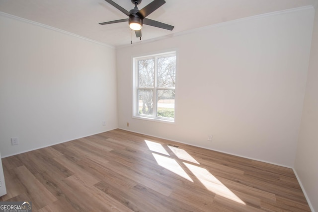 unfurnished room with a ceiling fan, wood finished floors, baseboards, and ornamental molding