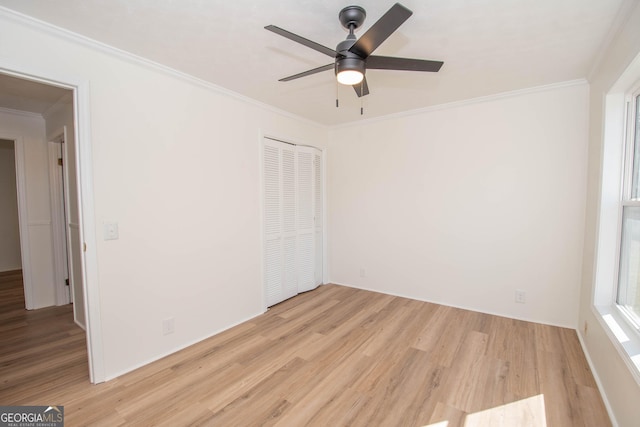 unfurnished bedroom featuring a closet, light wood-style floors, ornamental molding, and a ceiling fan