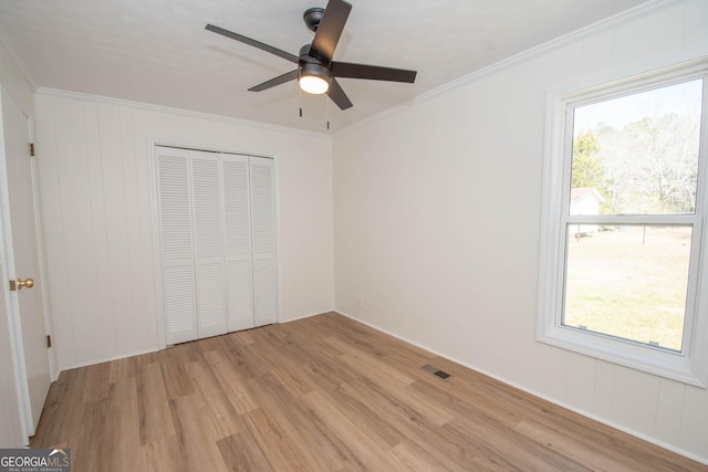 unfurnished bedroom with visible vents, multiple windows, light wood-style flooring, and ornamental molding