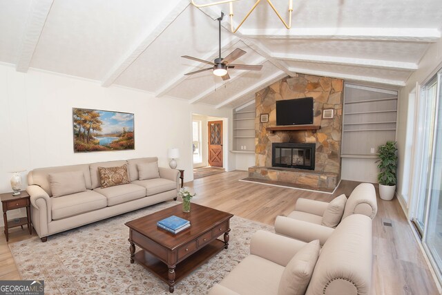 living area featuring a fireplace, vaulted ceiling with beams, wood finished floors, and plenty of natural light