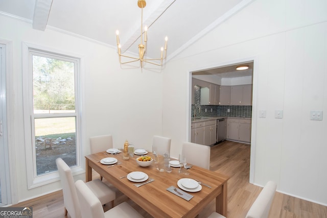 dining area with lofted ceiling, a notable chandelier, and light wood-style floors