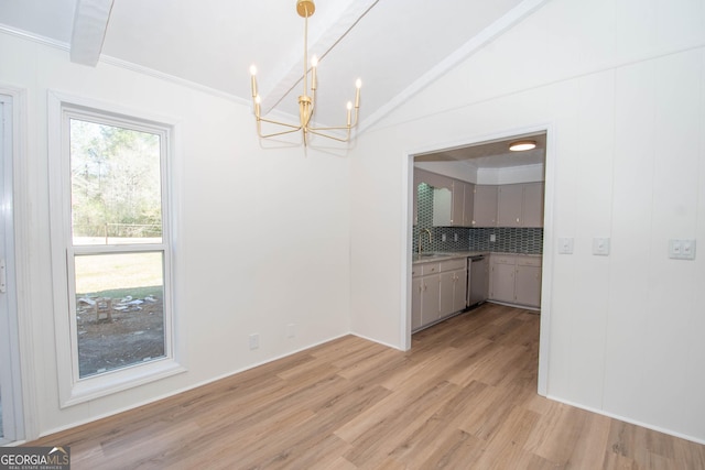 unfurnished dining area featuring a notable chandelier, light wood-type flooring, lofted ceiling, and a sink