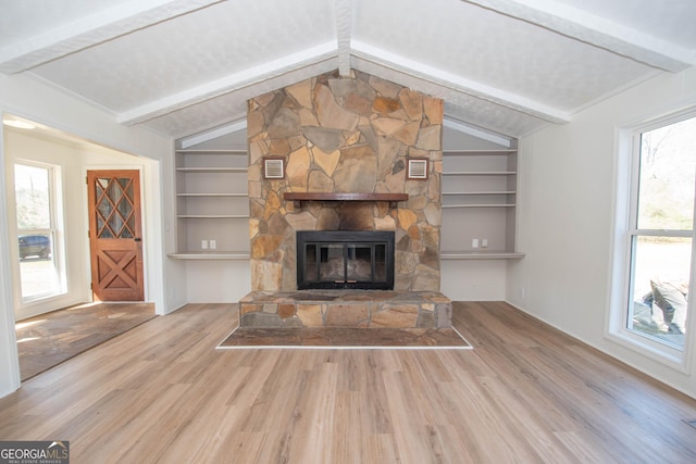 unfurnished living room with built in shelves, wood finished floors, visible vents, lofted ceiling with beams, and a fireplace