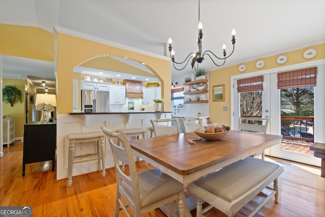 dining area with french doors, lofted ceiling, light wood-style floors, and ornamental molding