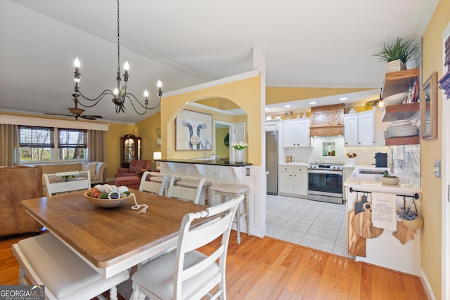 dining room featuring ceiling fan, lofted ceiling, light wood-style flooring, and ornamental molding