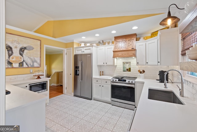 kitchen with a sink, ornamental molding, vaulted ceiling, white cabinets, and stainless steel appliances