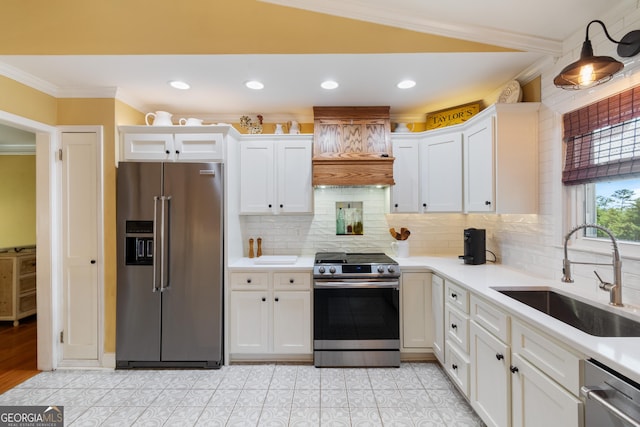 kitchen with a sink, stainless steel appliances, white cabinets, and crown molding