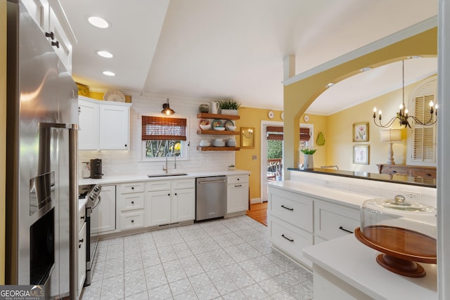 kitchen with decorative backsplash, appliances with stainless steel finishes, arched walkways, white cabinetry, and a sink