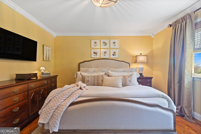 bedroom with wood finished floors and ornamental molding