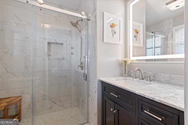 full bath with a marble finish shower and vanity