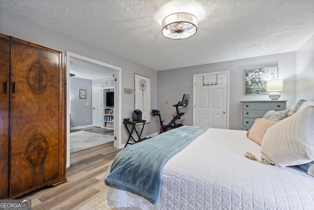 bedroom with baseboards, light wood-style floors, and a textured ceiling