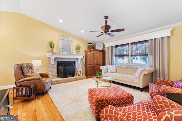 living area with vaulted ceiling, a fireplace, light wood-type flooring, and ornamental molding