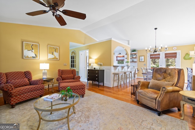 living area with ceiling fan with notable chandelier, lofted ceiling, wood finished floors, and ornamental molding