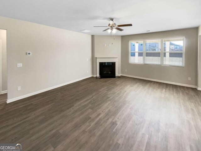 7644 Watson Cir, Locust Grove, GA 30248 - unfurnished living room featuring dark wood-type flooring, a ceiling fan, and a fireplace with flush hearth