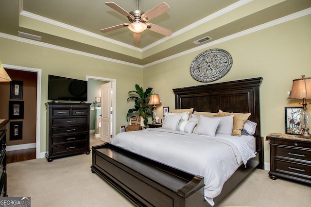 bedroom with baseboards, visible vents, a tray ceiling, light carpet, and crown molding