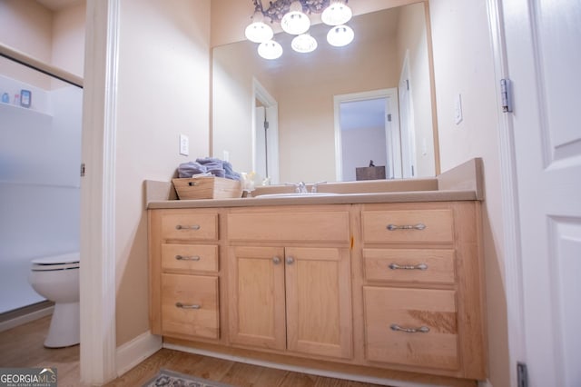 348 N Ridge Ln, Temple, GA 30179 - bathroom featuring wood finished floors, toilet, vanity, baseboards, and a notable chandelier