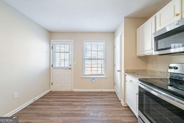 kitchen with dark wood finished floors, appliances with stainless steel finishes, white cabinetry, and light countertops