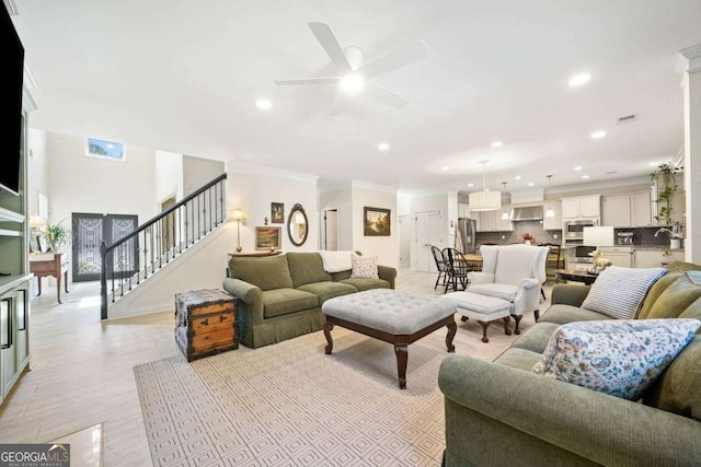 living room with stairway, a ceiling fan, light wood finished floors, recessed lighting, and ornamental molding