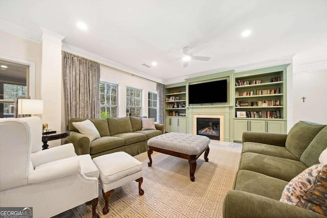 living area featuring a glass covered fireplace, crown molding, recessed lighting, and a ceiling fan