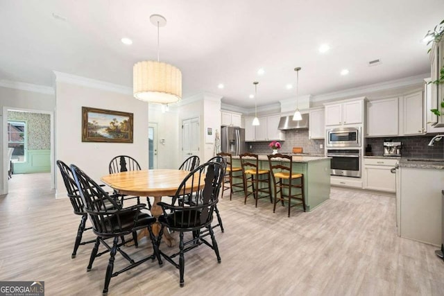 dining room with recessed lighting, light wood-style flooring, and crown molding