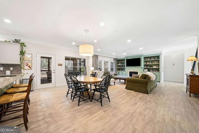 dining space with baseboards, recessed lighting, a fireplace, crown molding, and light wood-type flooring