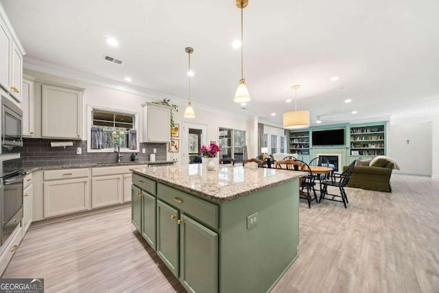 kitchen featuring visible vents, a center island, green cabinets, open floor plan, and ornamental molding