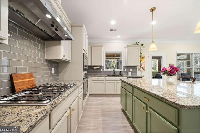 kitchen with visible vents, green cabinets, stainless steel appliances, wall chimney exhaust hood, and a sink