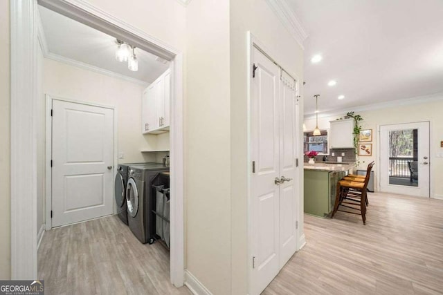 laundry area with light wood-style flooring, ornamental molding, and washer and clothes dryer