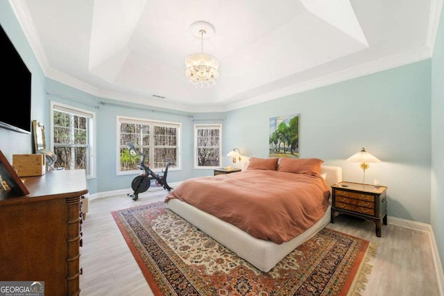 bedroom with light wood finished floors, visible vents, baseboards, a tray ceiling, and an inviting chandelier