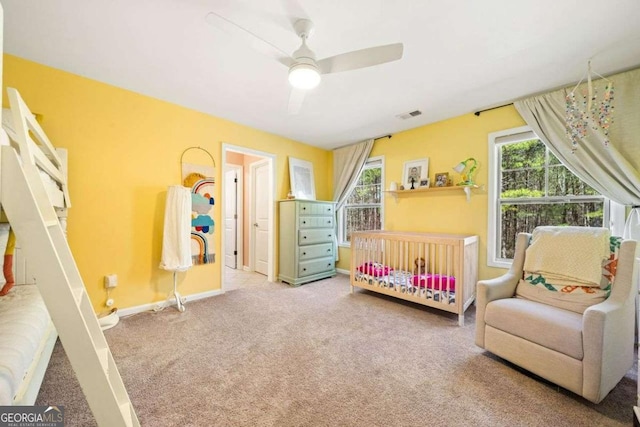 carpeted bedroom featuring multiple windows, baseboards, visible vents, and ceiling fan