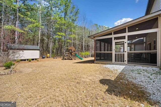 view of yard featuring an outdoor structure, a playground, and a sunroom