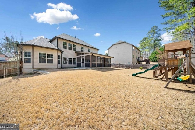 rear view of property with a lawn, fence private yard, a playground, and a sunroom