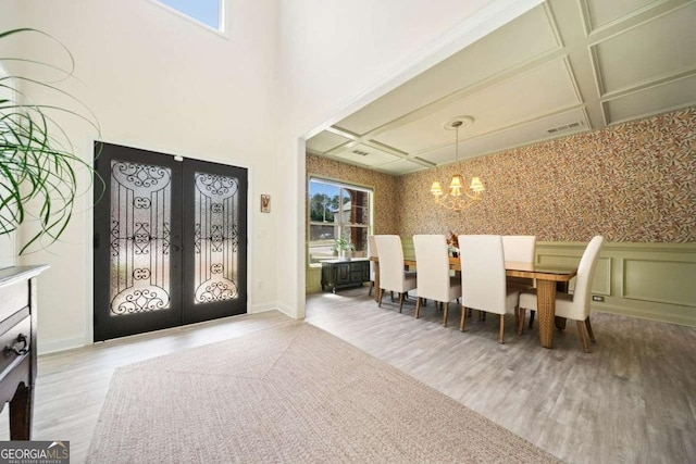 entrance foyer with wallpapered walls, french doors, a wainscoted wall, and a chandelier