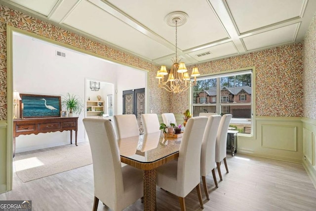 dining room with a wainscoted wall, an inviting chandelier, visible vents, and wallpapered walls