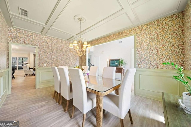 dining space featuring a wainscoted wall, light wood finished floors, visible vents, wallpapered walls, and coffered ceiling