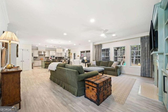 living area with a fireplace with flush hearth, recessed lighting, ornamental molding, ceiling fan, and light wood-style floors