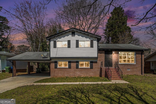 split level home featuring a carport, a front lawn, concrete driveway, and brick siding